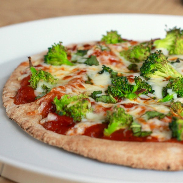 A pizza with broccoli, green peppers, cheese, and sauce.