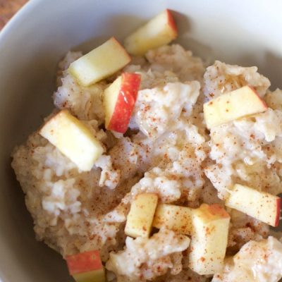 A bowl of oatmeal mixed with apples and cinnamon.