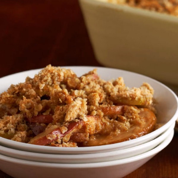 Bowl of apple crisp topped with nuts and oatmeal.