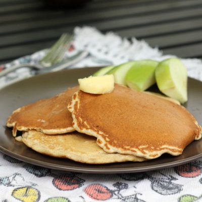 A plate of apple stuffed pancakes with a side of sliced apples.