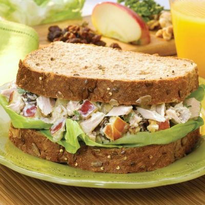 A whole wheat sandwich with mix of apple, tuna, mustard, lettuce, and yogurt.