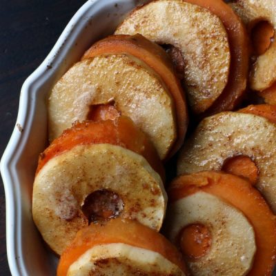 Sliced baked apples and sliced sweet potatoes layered one on top of another topped with spices.