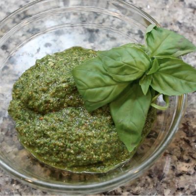 Bowl of basil pesto with a sprig of basil.