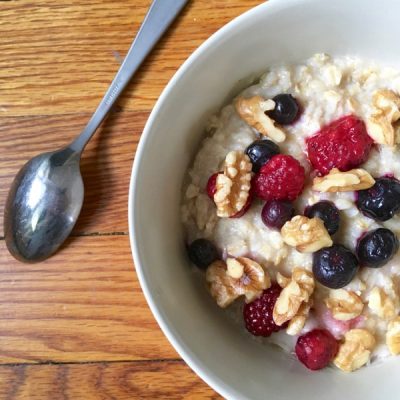 Bowl of oatmeal topped with blueberries, raspberries, and walnuts.