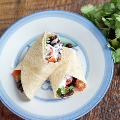 Tortilla wrapped into a burrito stuffed with black beans, tomatoes, cilantro, and plain yogurt.