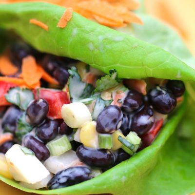 Black beans and corn mixed with diced red peppers, green onion, and carrots wrapped in a leaf of lettuce.