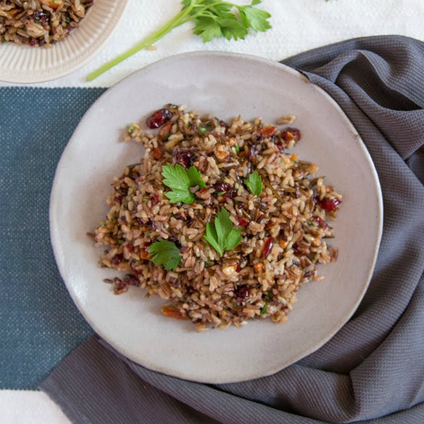 Plate of brown rice, mixed with chopped onions, celery, and raisins topped with sage.