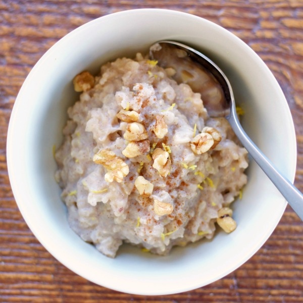 Bowl of cooked brown rice pudding made with bananas, milk, brown sugar, and cinnamon.