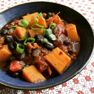 Cubed butternut squash mixed with black beans, diced onions, carrots, and tomatoes, and topped with sliced green onions.