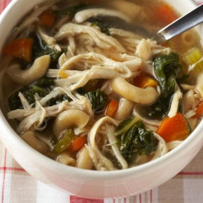 Bowl of cubed chicken soup with noodles, kale and carrots.