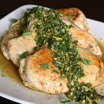 Cooked and browned chicken breasts topped with chopped parsley and garlic.