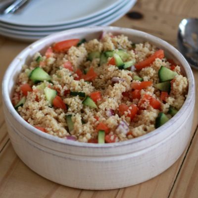 Bowl of couscous mixed with diced tomato and cucumber.