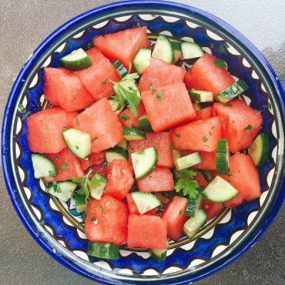 Bowl of watermelon and cucumber garnished with lime juice and parsley