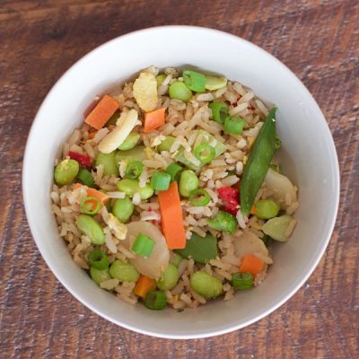 Bowl of rice with carrots, snap peas, edamame, and green onions