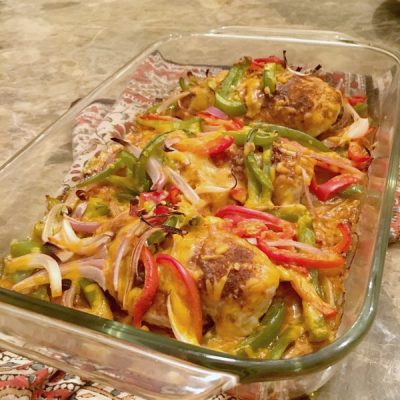 A savory casserole dish brimming with chicken, peppers, and onions, topped with melted shredded cheese