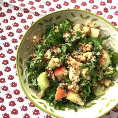 Bowl of salad with apples, walnuts, kale, celery and quinoa topped with a cinnamon vinaigrette