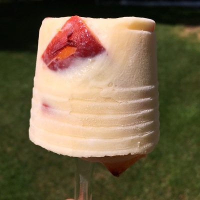 Peach popsicle made of sliced peaches, yogurt, and orange juice