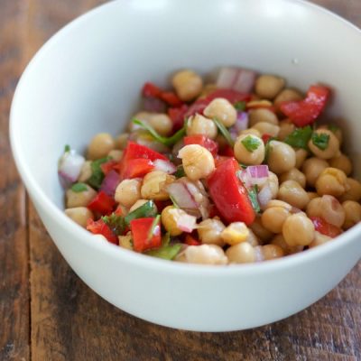 Bowl of boiled bean mixed with chickpeas, diced red pepper, onions topped with chopped cilantro.