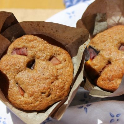 Peach bran muffins in paper wrappers on a white and blue cloth.