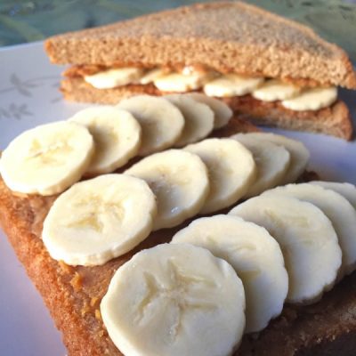 Sandwich with two whole wheat slices of bread filled with bananas creamy pumpkin, and peanut butter.