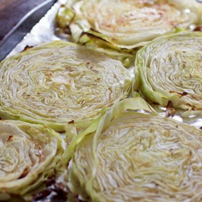 Slices of roasted cabbage on a foil lined sheet pan.