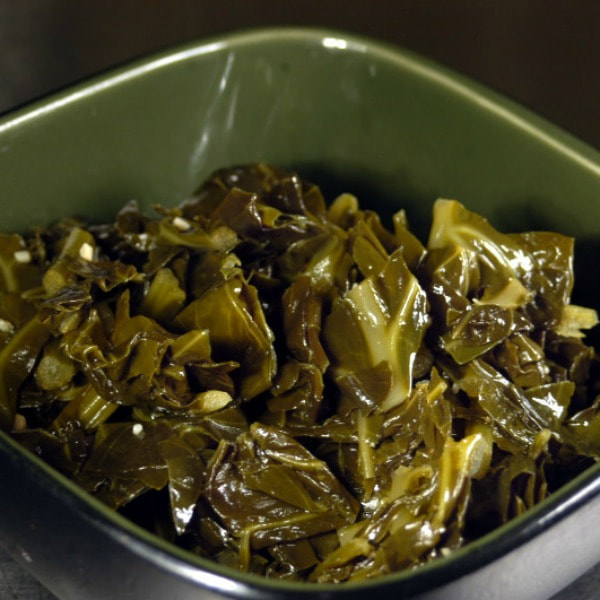 A bowl of cooked kale with chopped turkey breast.