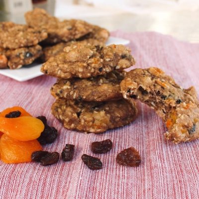 A stack of fruity cookies, slightly browed with dried apricots and raisins nearby.