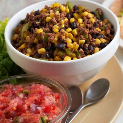Bowl of ground beef, corn, black peppers, diced green peppers with a bowl of salsa next to it.