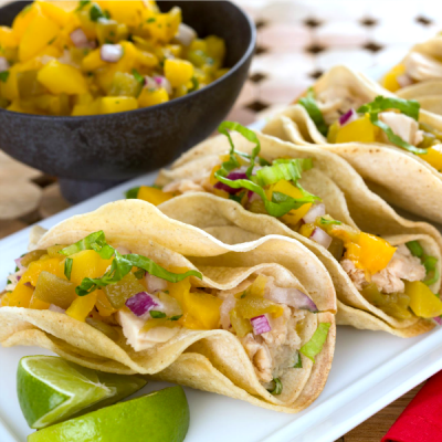 Tortillas rolled into taco shapes stuffed with flaked tuna, cabbage, shredded Monterey cheese, with a bowl of peach salsa on the side.