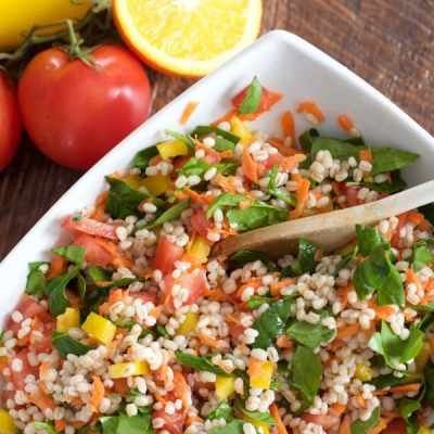 Bowl of barley mixed with chickpeas, tomatoes, and diced yellow pepper, and chopped spinach.