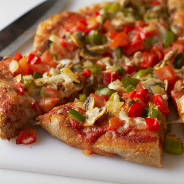 Plate of pizza slices covered in tomatoes, red and green peppers, and onion.