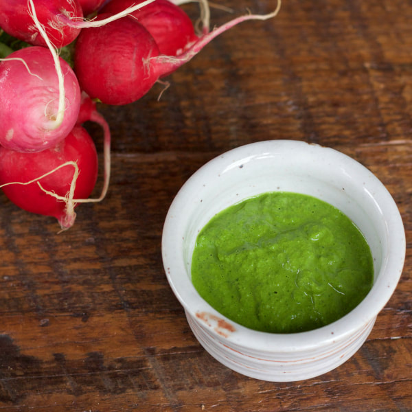 Small bowl of radish topped greens pureed into a pesto-like spread.