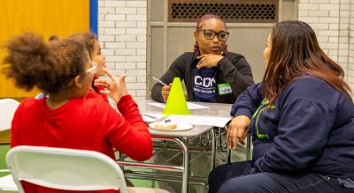UConn Grad Student with UConn HNS t-shirt sitting at table with family in conversation