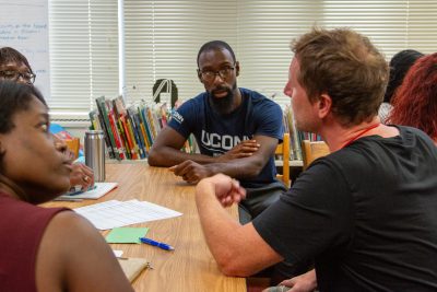 A group of teachers sit around a table with notes on it deep in discussion.